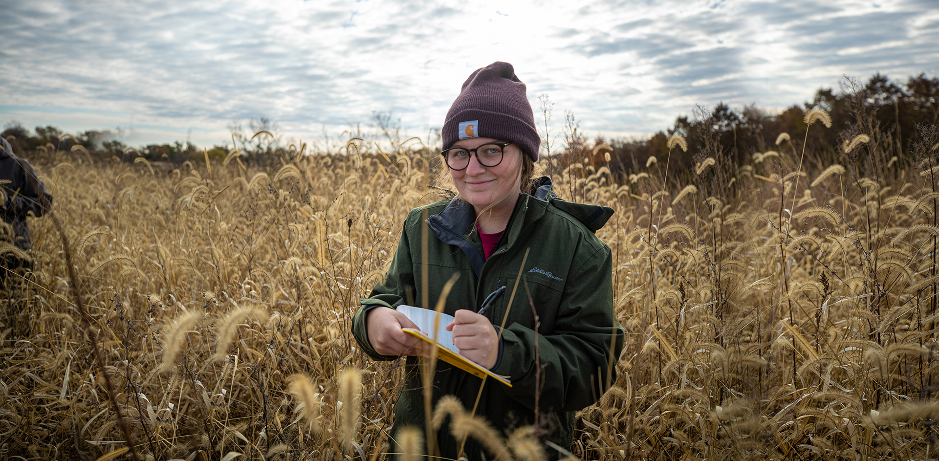 student taking field notes on a prairie 