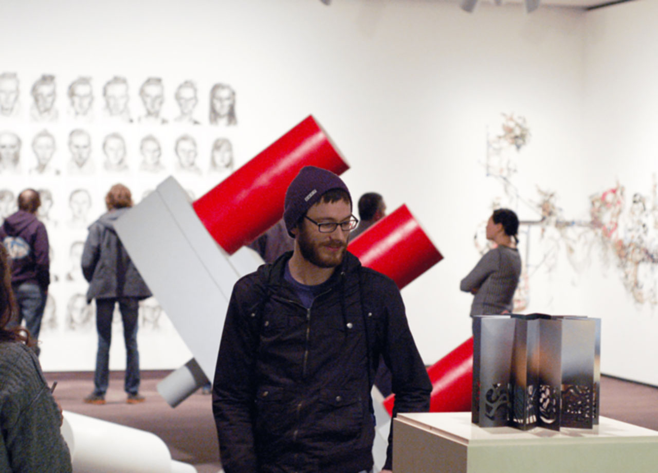 Student in an art gallery examining a sculpture.