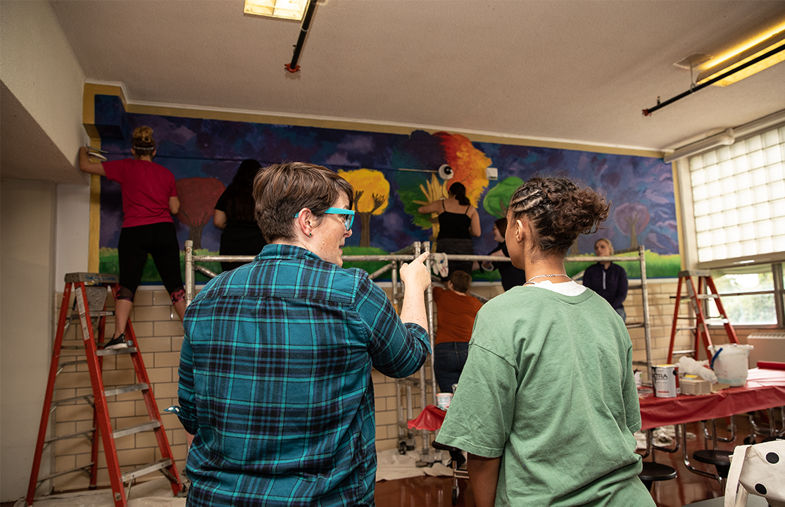 Two students painting a murial.