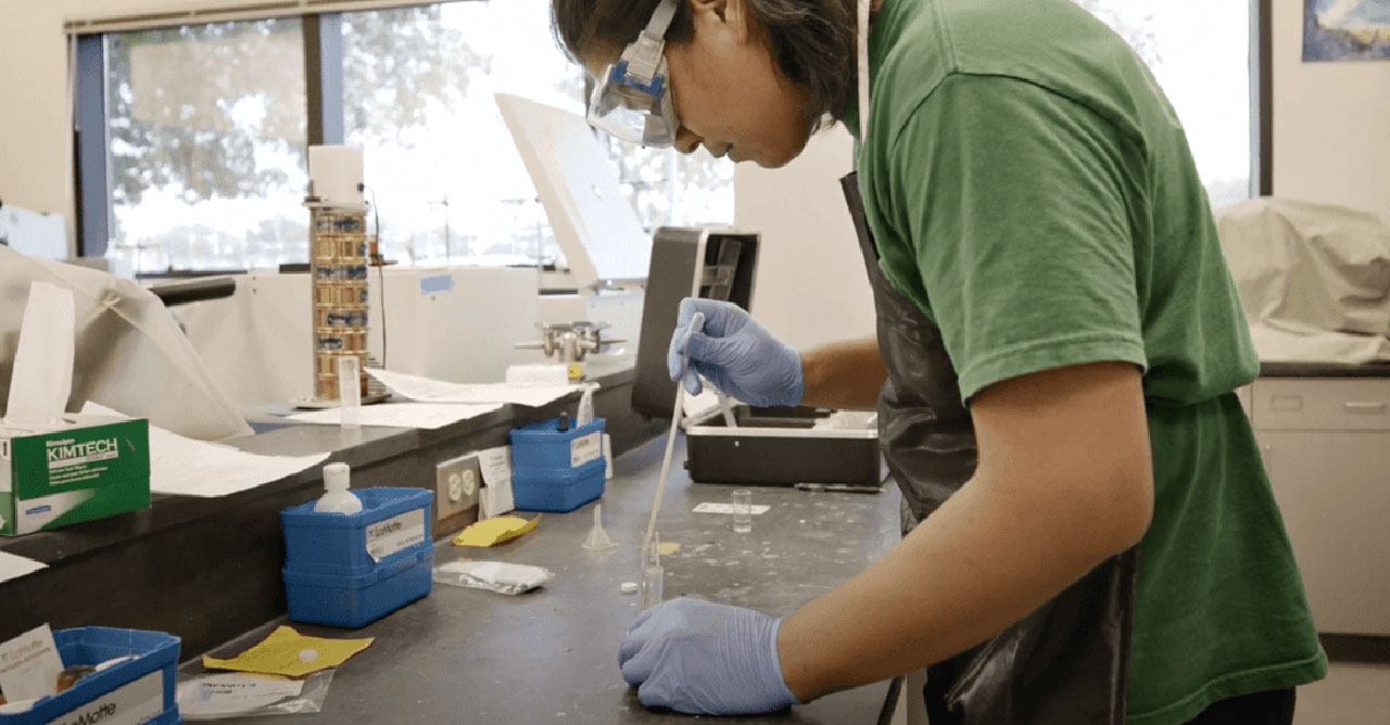 Student in a lab using a dropper during an experiment.