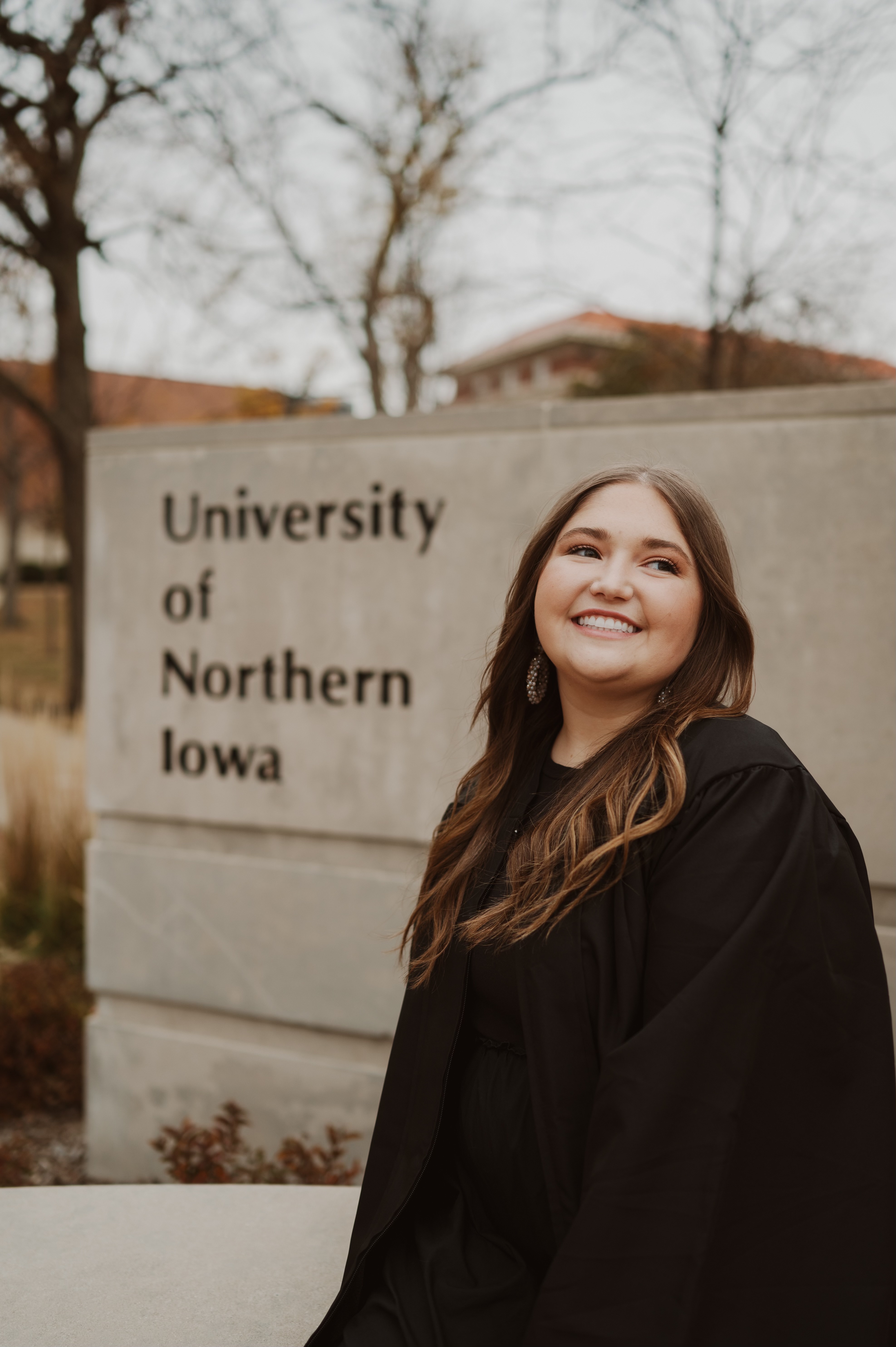 Averee sitting in front of the university of northern iowa sign
