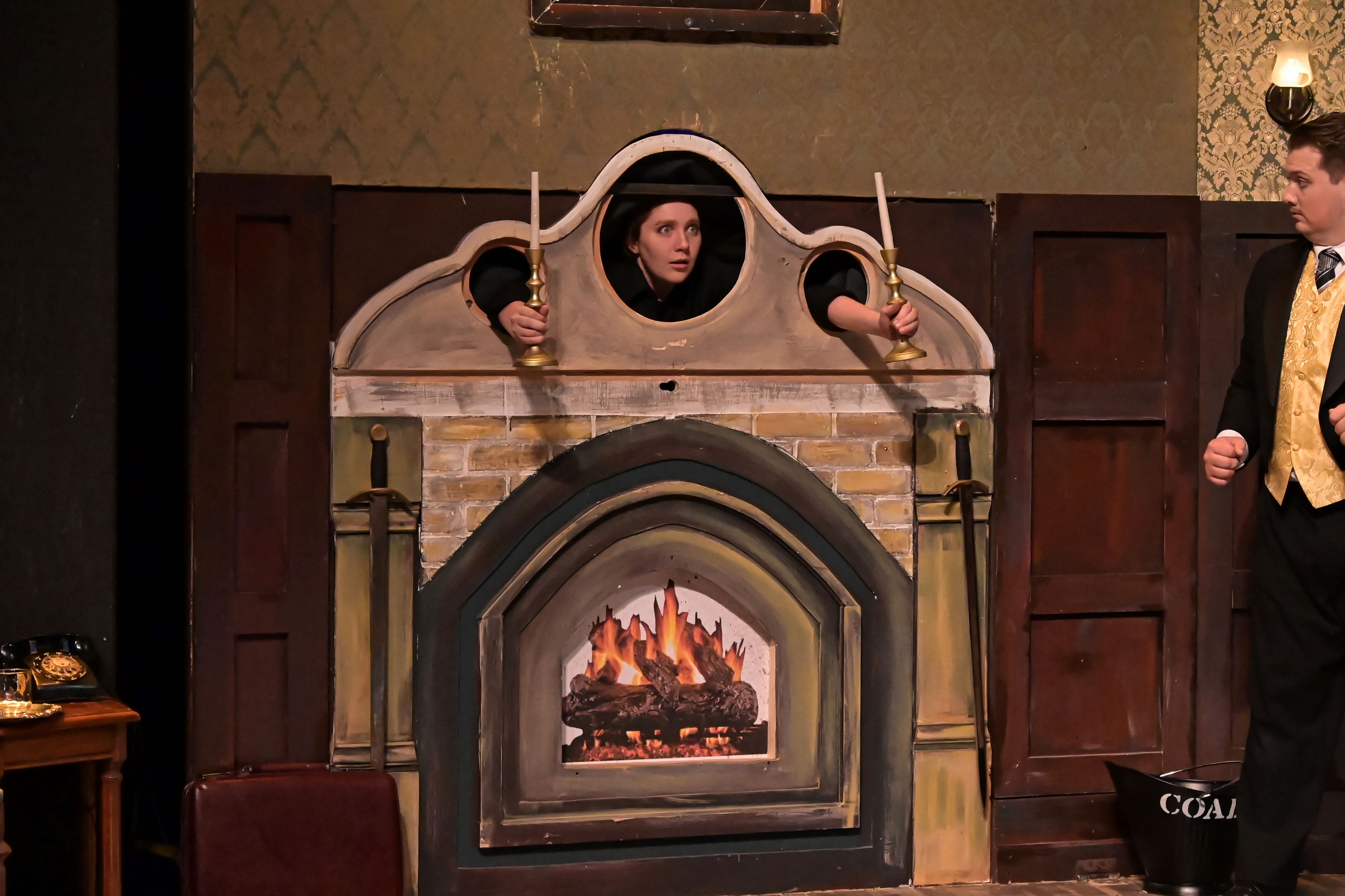 The stage manager looks out from the fireplace in horror