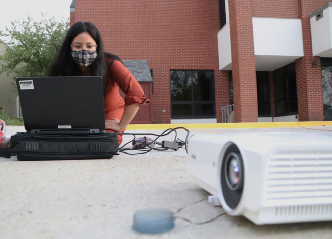 Student with a projector attached to her laptop.