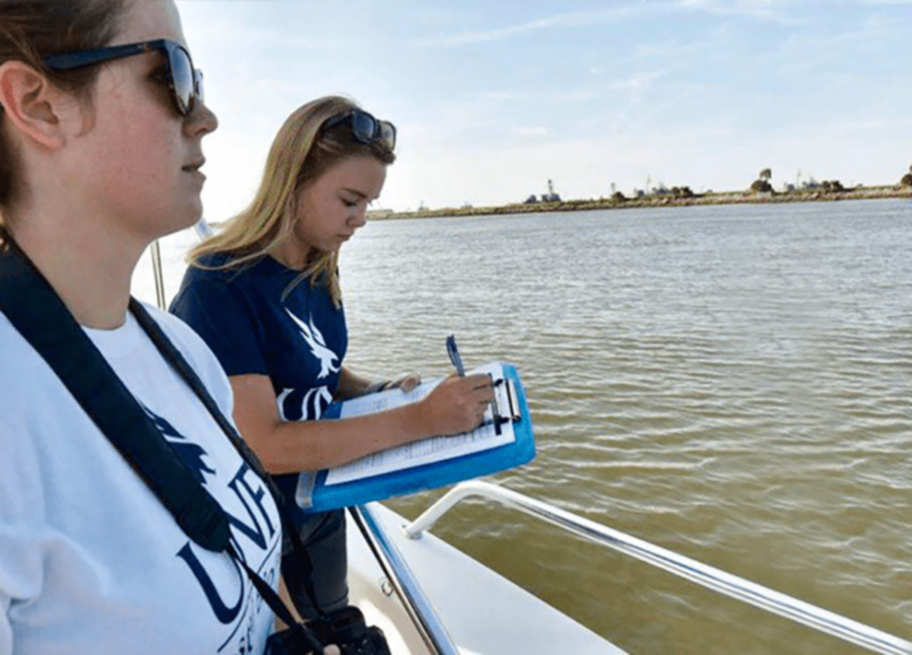 Students on a boat taking notes.