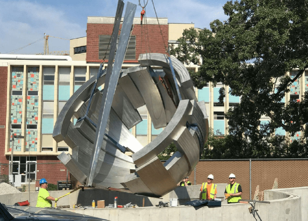Large scuplture being installed with the help of a crane.