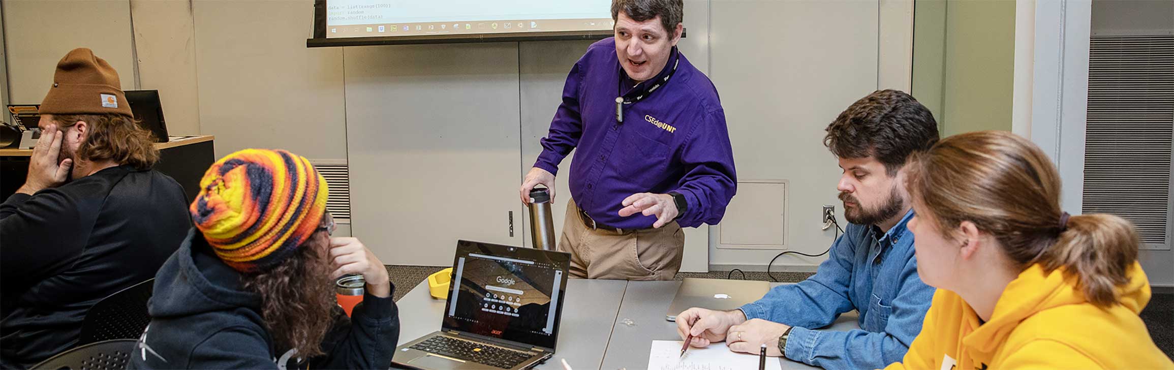 Professor showing code to students in a classroom.
