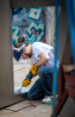 Artist working on a sculpture using a drill.