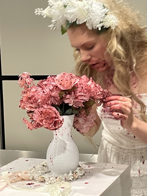 Girl smelling flowers with red paint on them