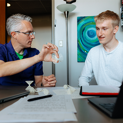 a male student and faculty member talking in an office setting
