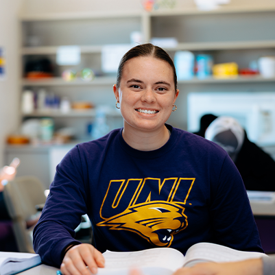 female student sitting at table with textbook