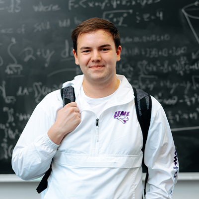 male student standing in front of chalkboard with math equations 