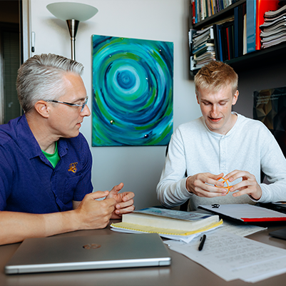 male professor and male student chatting in an office 