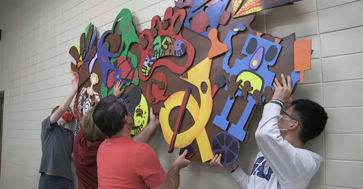 Students mounting installation art on a wall.