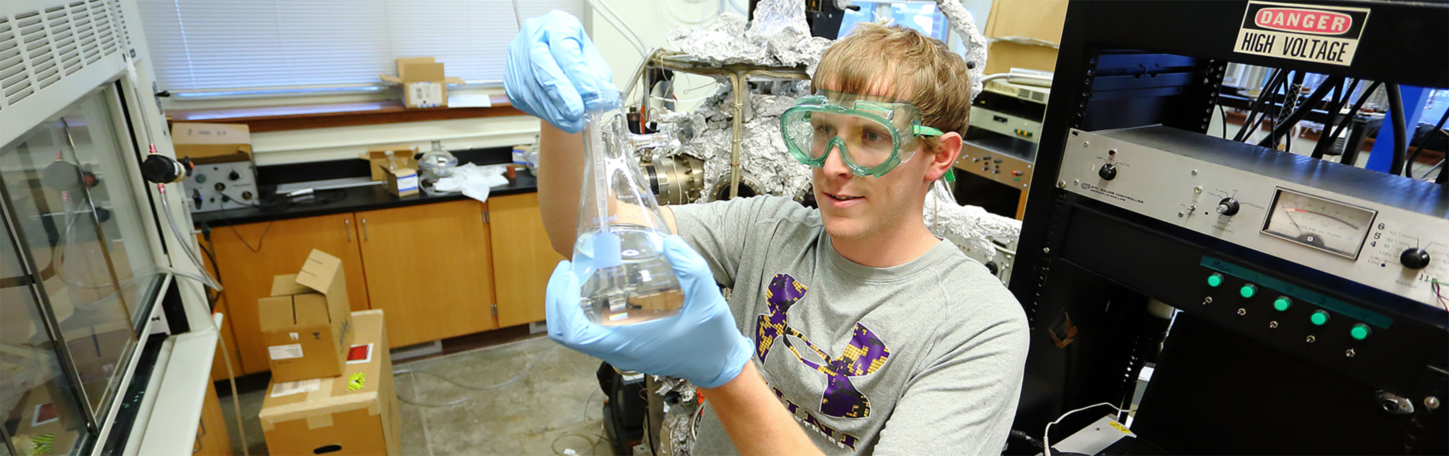 Student with safety glasses on mixing some chemicals.