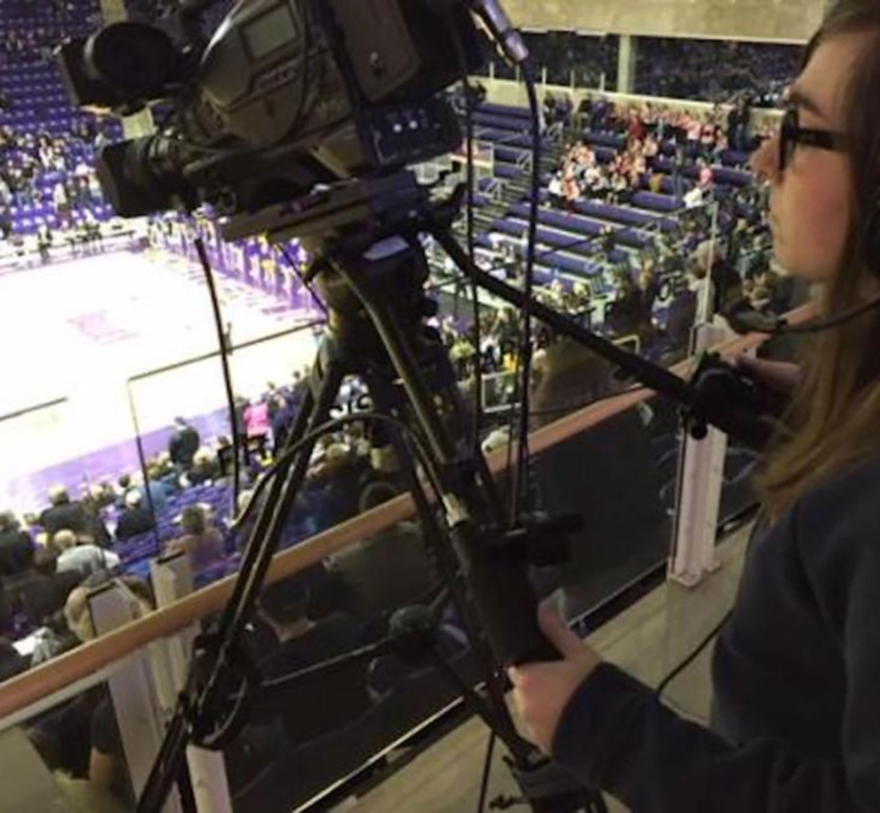 Student with a camera filming a basketball game.