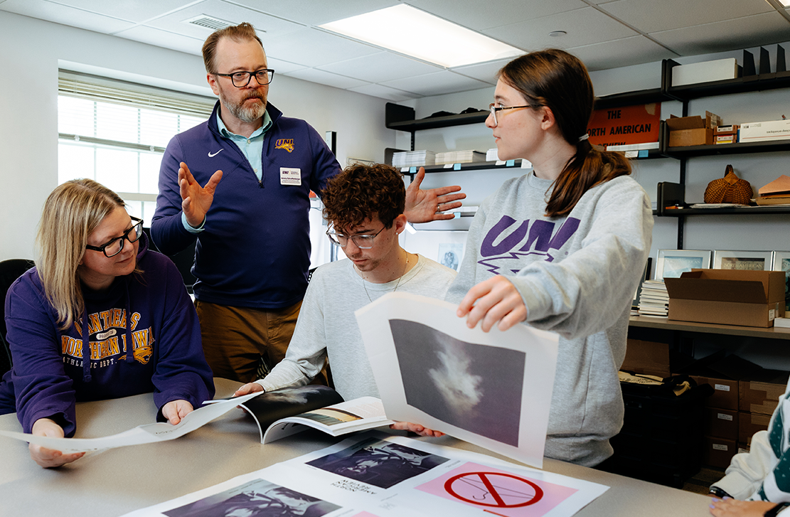 students looking over magazine layouts with professor