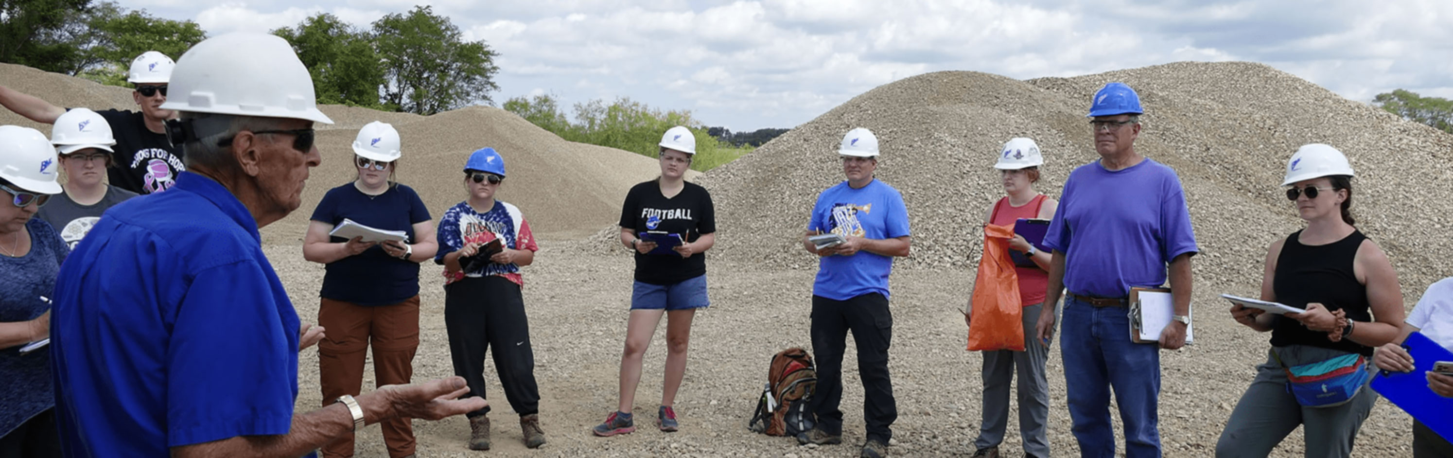 Students on a gravel site listening to a lecture.