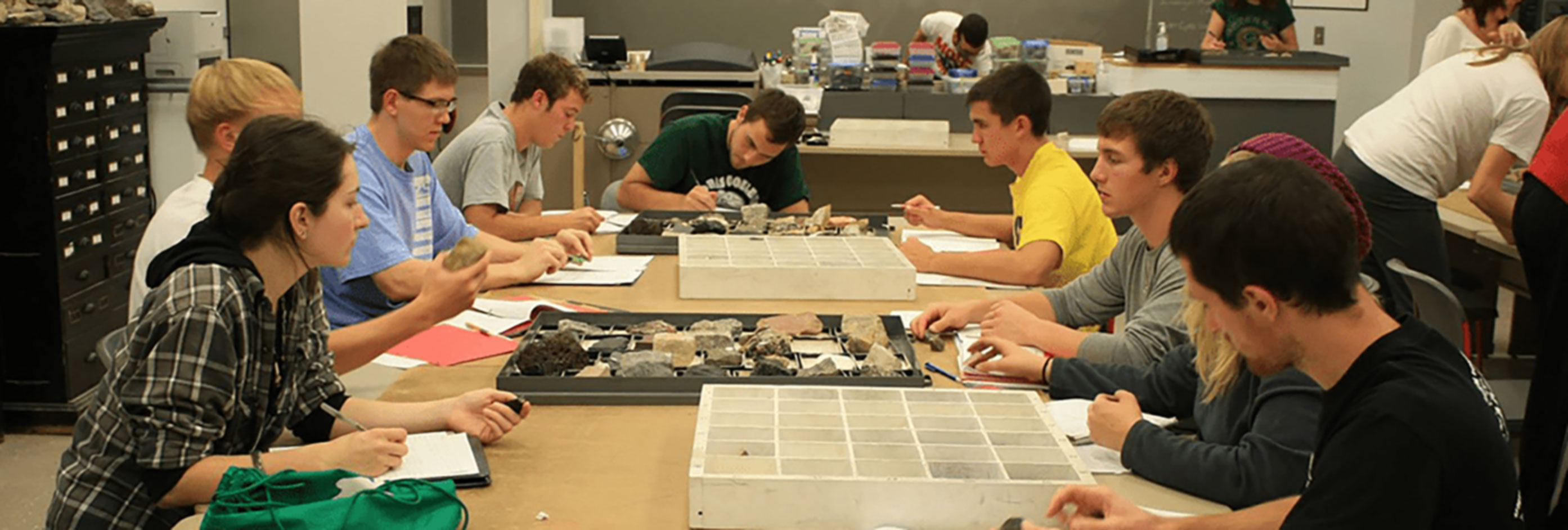 Students with sample rocks on a table experimenting.