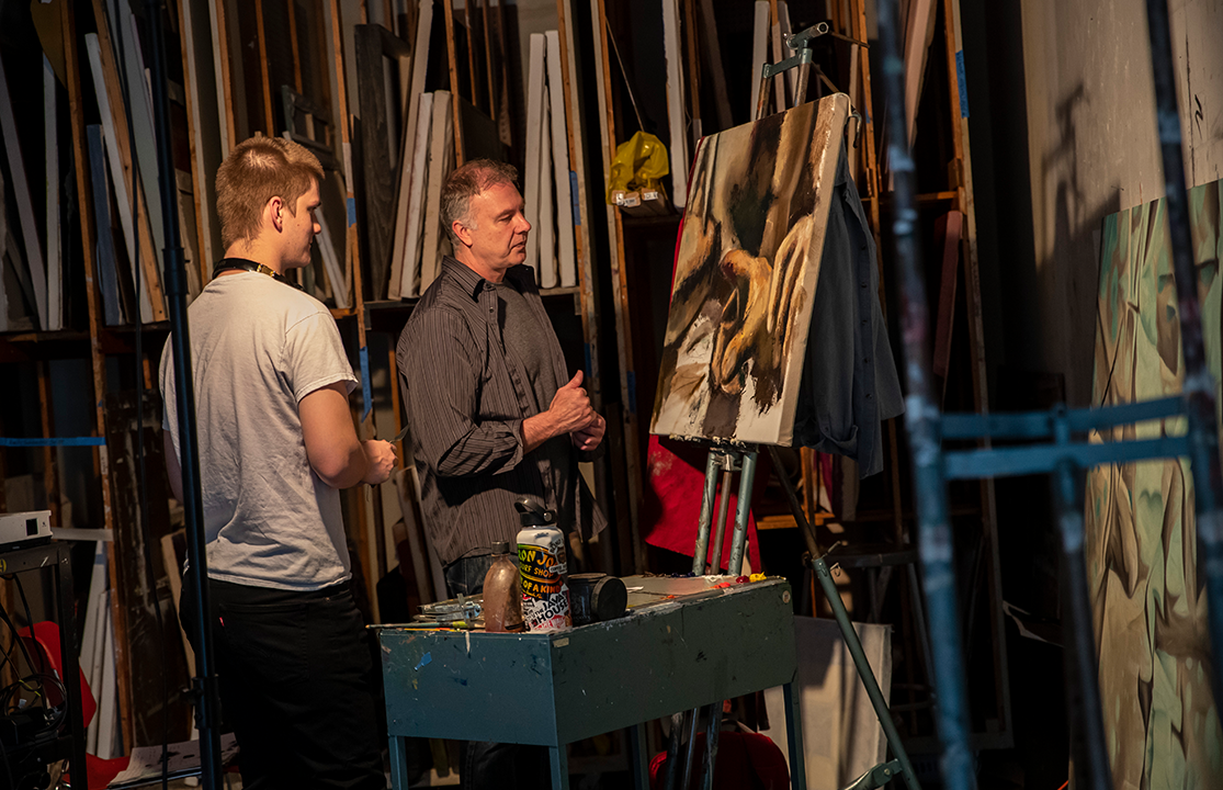 Student and an instructor looking at a painting in an art studio.