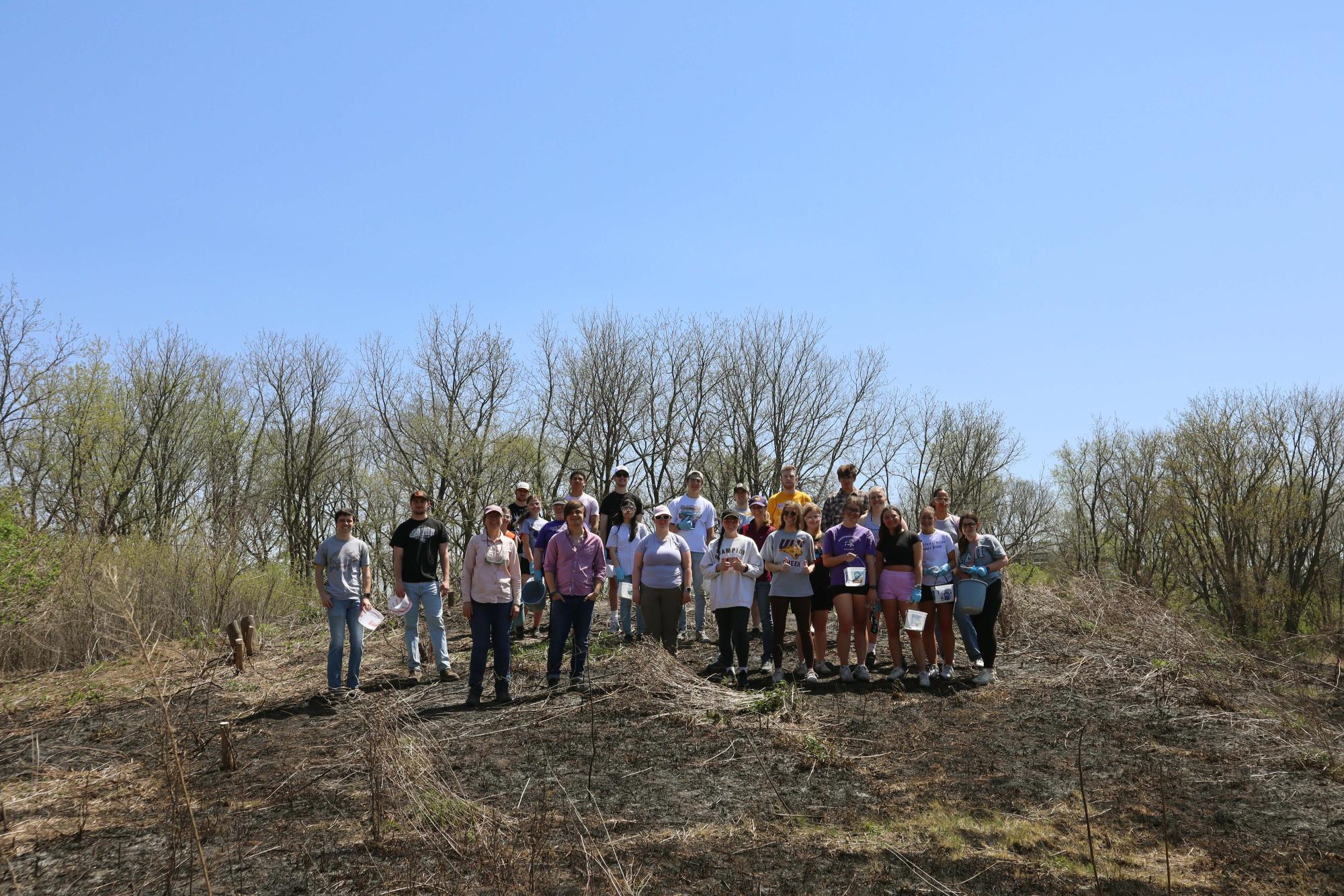 Two classes stand on top of the mound after completing work for the day