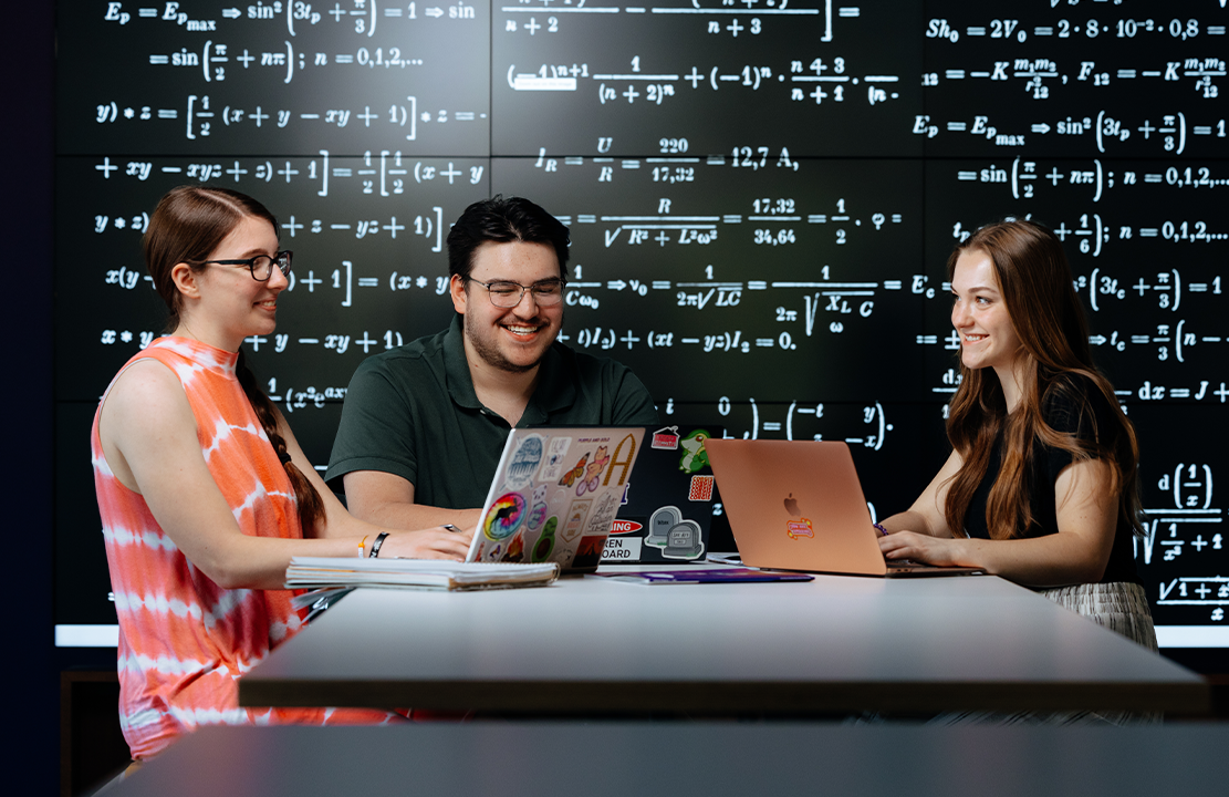 three students working together on laptops 