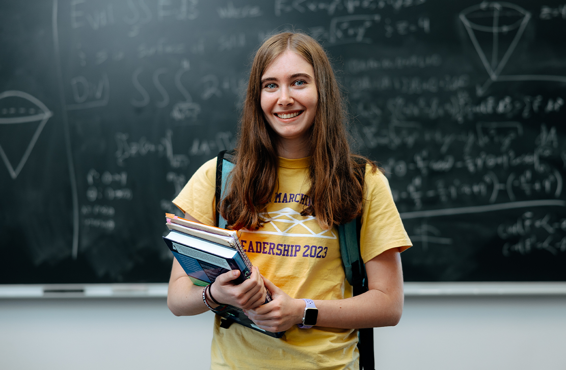 image of a student in front of a chalkboard with math problems 