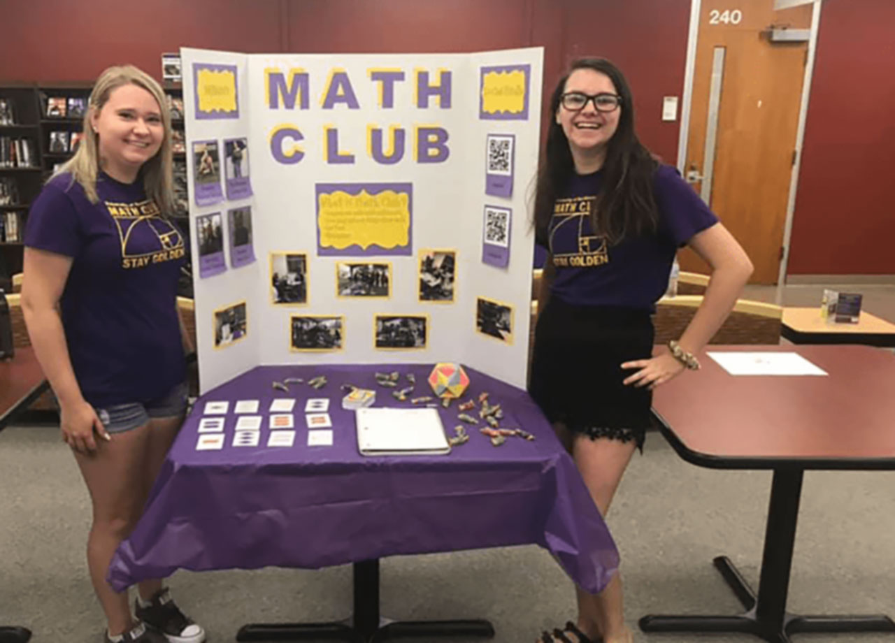 Math club students displaying their poster highlighting club involvement.
