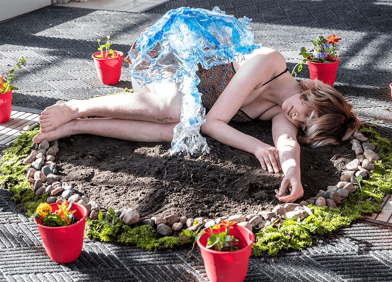 Lady in a circle of dirt surrounded by plant life, sleeping.