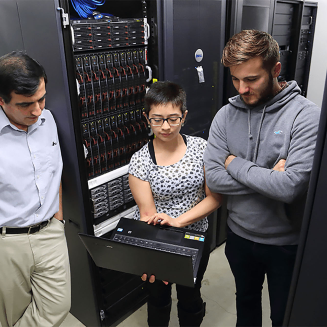 Students in a server room next to a server rack.