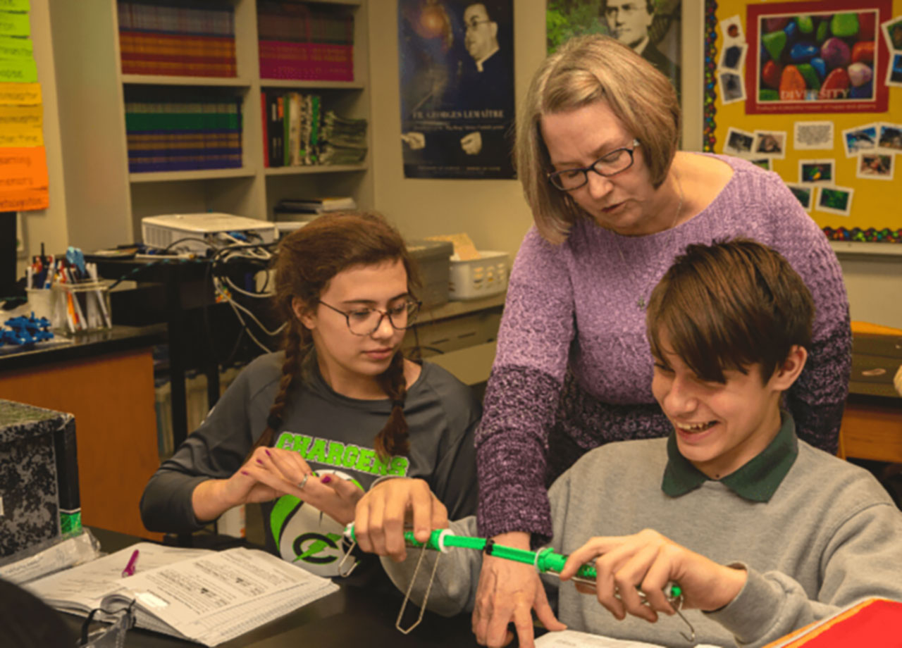 Instructor working with young students during an experiment.