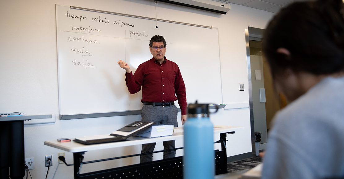 professor in a spanish class pointing at the whiteboard 