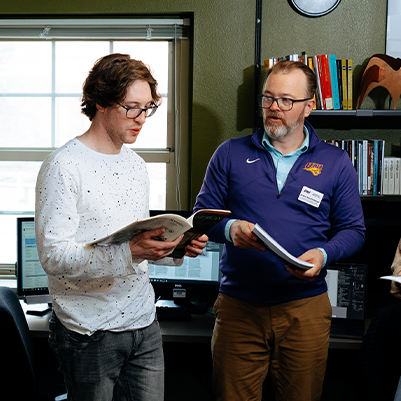 student and faculty looking at a book together