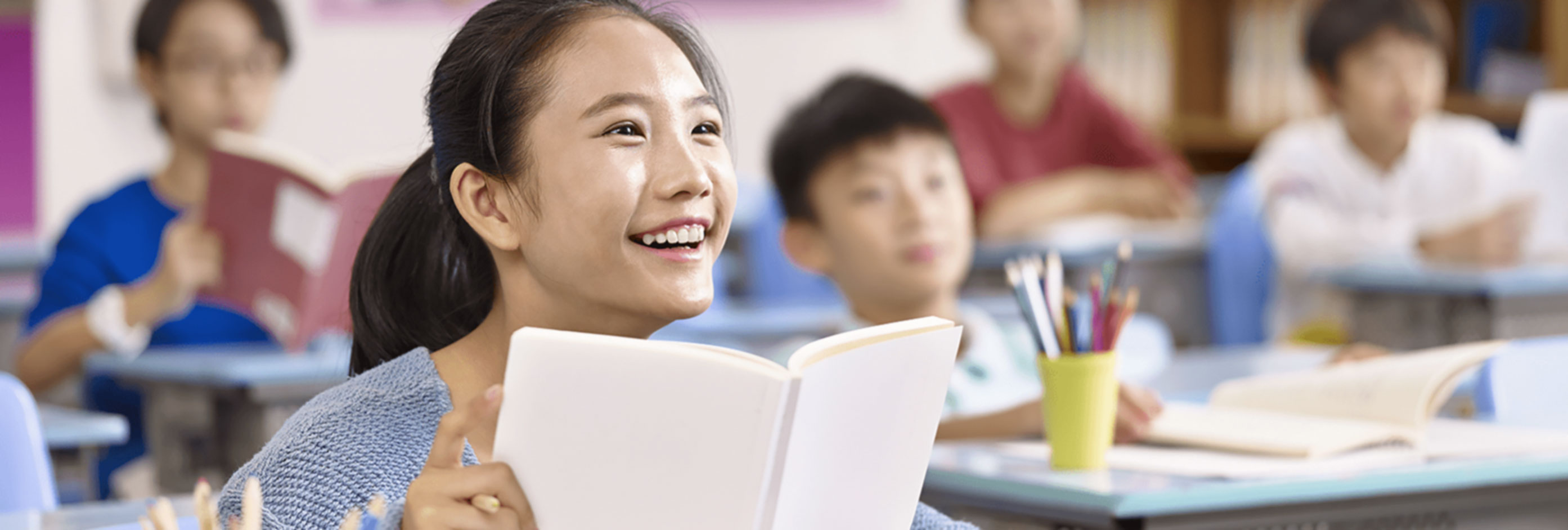 Student smiling while holding a book.