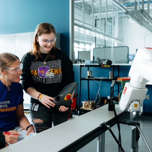 Students operate an ABB robot with a handheld device in applied engineering lab