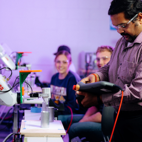 Students observe a professor demonstrating an ABB robot in applied engineering lab